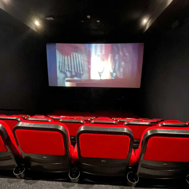 Les fauteuils rouges et l'écran d'une salle de cinéma