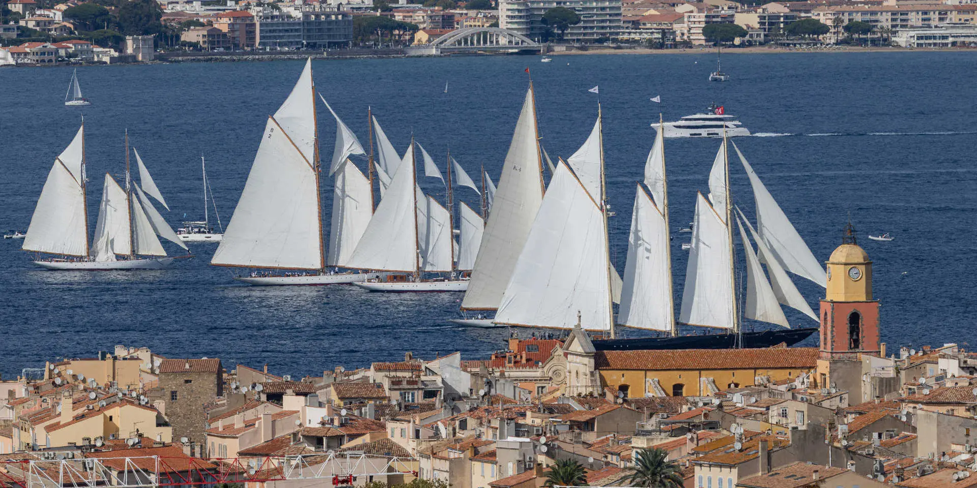 Des voiliers anciens naviguent devant le vieux village de Saint-Tropez