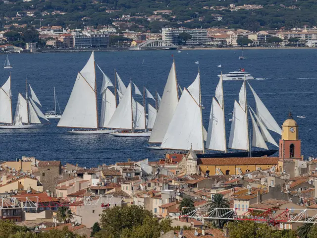 Des voiliers anciens naviguent devant le vieux village de Saint-Tropez